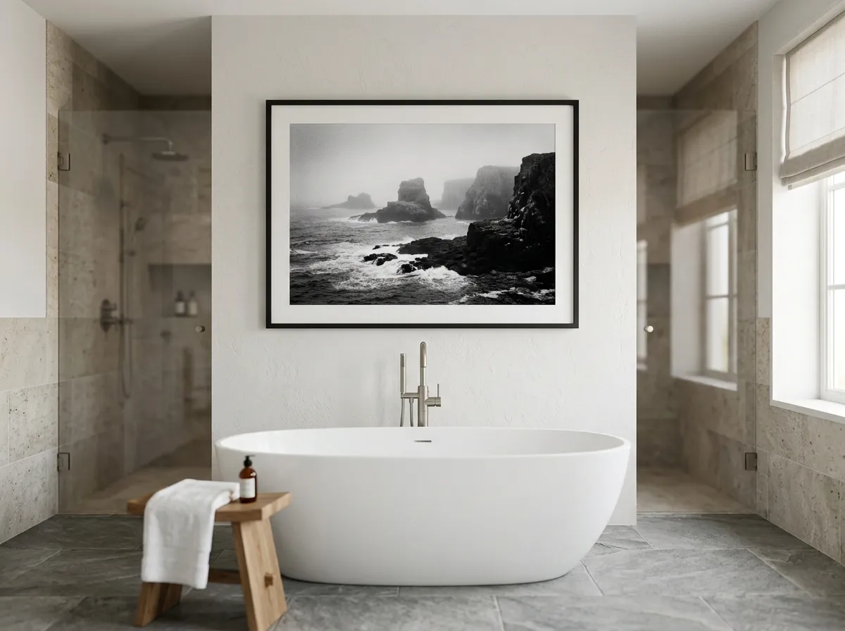 A high-contrast black and white coastal photograph on a dry feature wall in a spa-style bathroom
