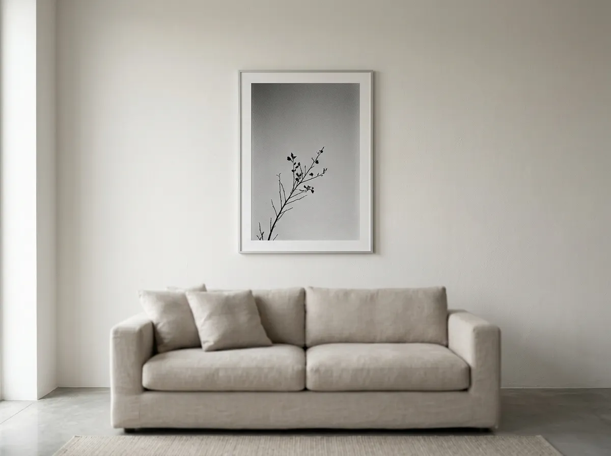 A single high-contrast monochrome photograph above a minimalist living room sofa with generous negative space